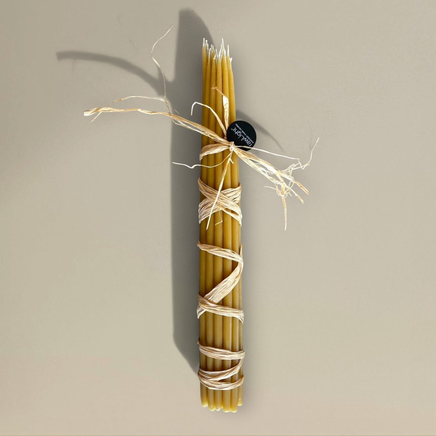 Bundle of 22 rawLight beeswax prayer candles, 500mm tall, tied with raffia, natural golden amber colour.