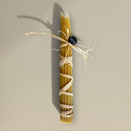 Bundle of 22 rawLight beeswax prayer candles, 500mm tall, tied with raffia, natural golden amber colour.
